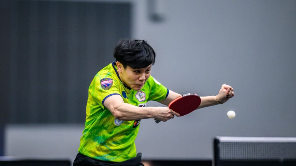Atleta de tênis de mesa executando golpe ofensivo durante partida, ilustrando treinamento técnico no tênis de mesa.