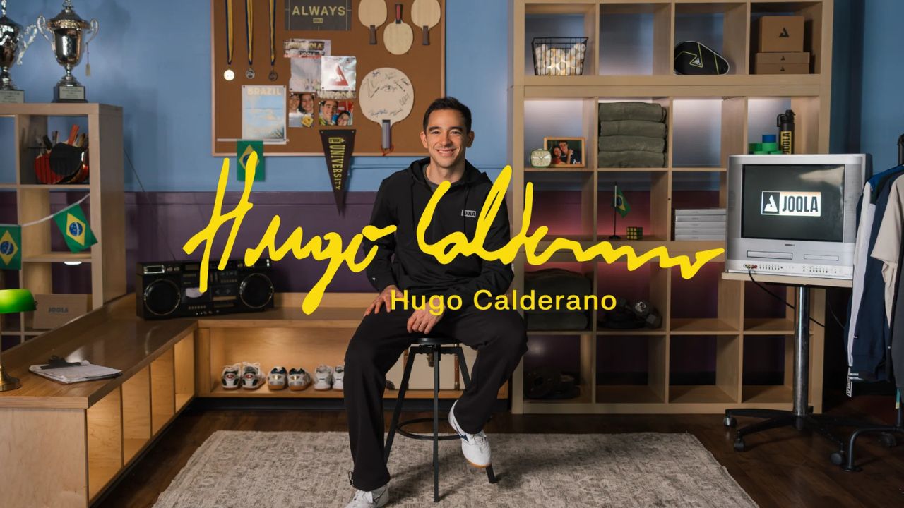 Hugo Calderano sentado em ambiente de campanha oficial da Joola, com sua assinatura em destaque, no anúncio como novo atleta da marca.