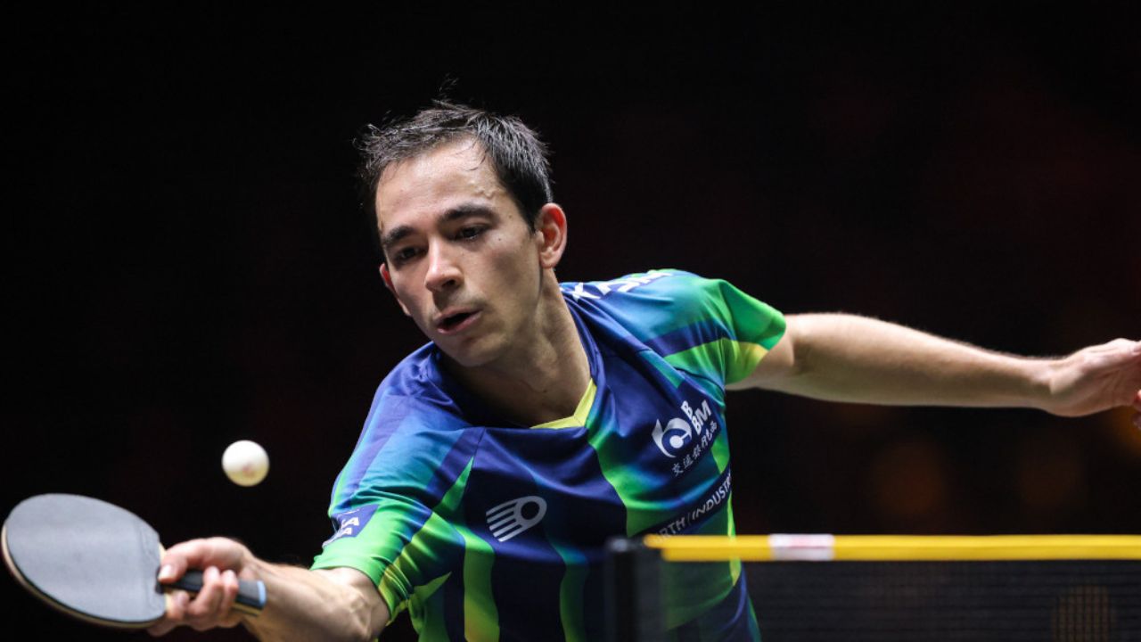 Hugo Calderano executando um golpe ofensivo durante partida internacional de tênis de mesa.